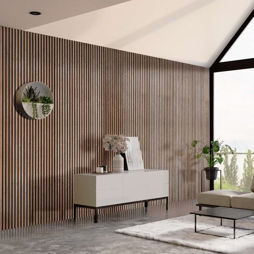 Sala moderna con pared revestida por paneles de listones verticales WoodUpp en madera natural con ranuras oscuras, creando textura y calidez. Incluye un aparador blanco bajo, mesa de centro negra, sofá, alfombra clara y maceteros junto a un gran ventanal que aporta luz.