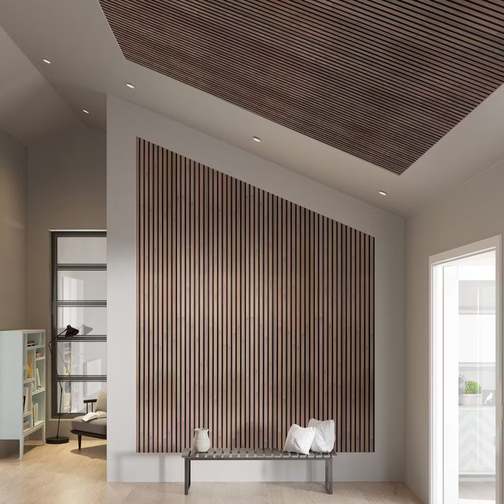 Interior moderno con paneles WoodUpp de lamas de madera en pared y techo: listones verticales y horizontales de tono nogal oscuro con ranuras negras, aportando textura acústica; delante, banco metálico de listones con cojines blancos y jarrón decorativo sobre suelo claro.